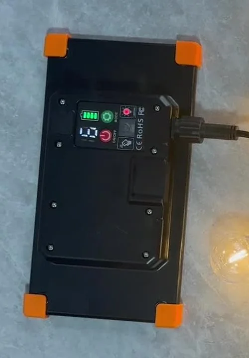 Close-up of a black control box with orange corner guards and a connected cable